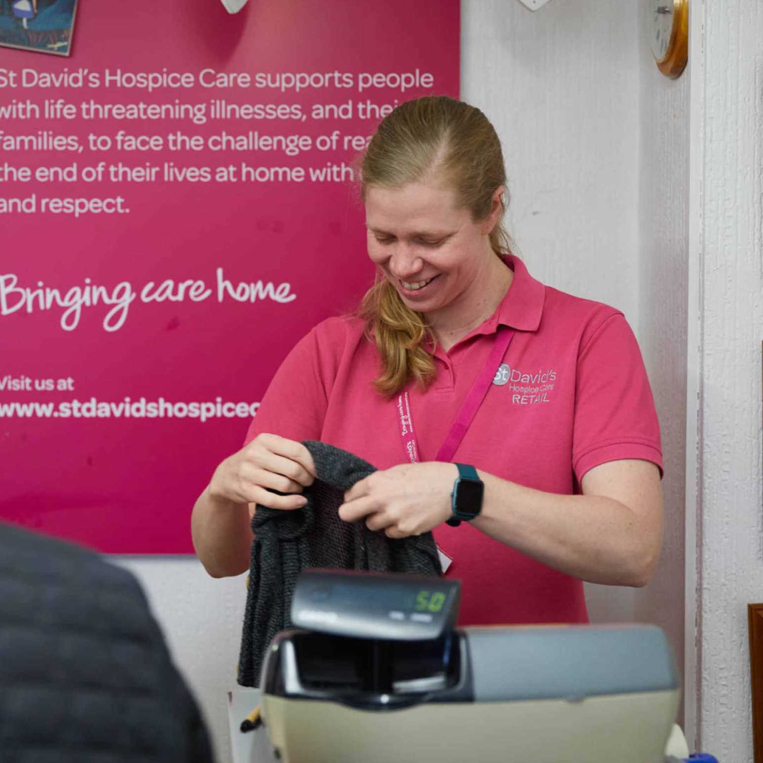 A shop worker in our St David's Hospice Care charity shop folding clothes