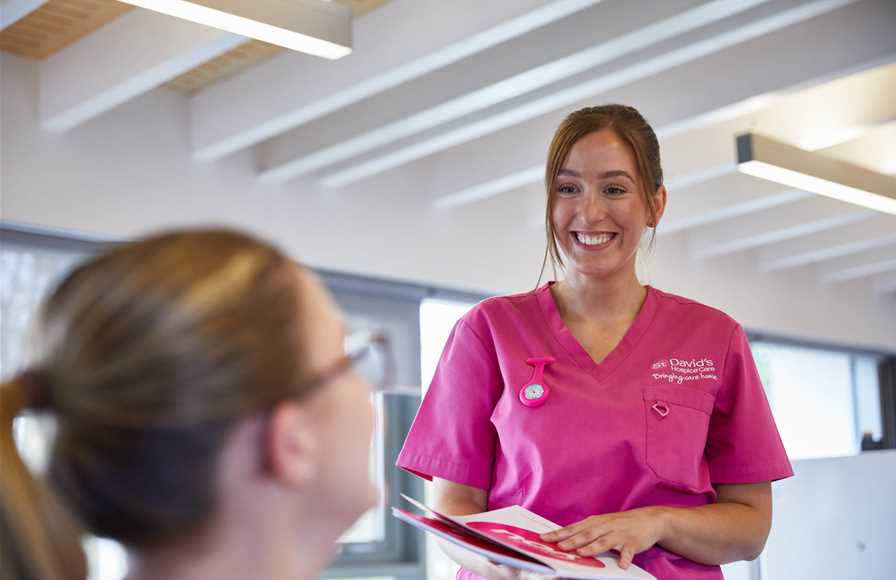Female nurse wearing pink scrubs smiling